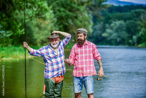 male friendship. family bonding. father and son fishing. hobby and sport activity. Trout bait. two happy fisherman with fishing rods. summer weekend. mature men fisher. Family Reunion