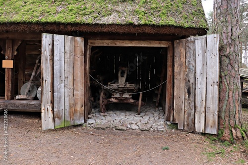 An old cart stands in a thatched wooden shed in the village