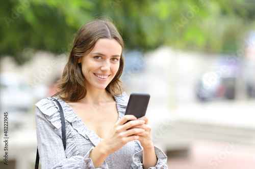 Happy woman holding phone looking at camera
