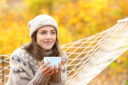 Happy woman contemplating holding coffee mug in autumn © PheelingsMedia