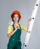 girl child wearing uniform and helmet while working in workshop with painting brush on ladder, labor day