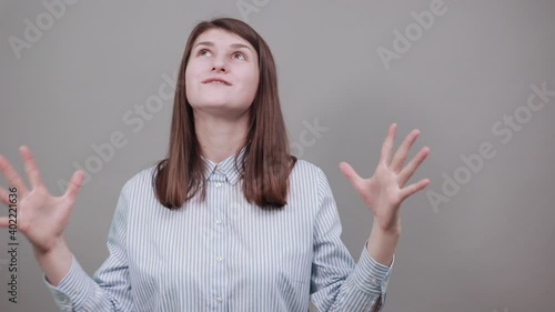 Wallpaper Mural Palms up, place your product here, raising arms wide spread is catching something. Young attractive woman, dressed blue shirt with brown eyes, brunette hair, grey background Torontodigital.ca