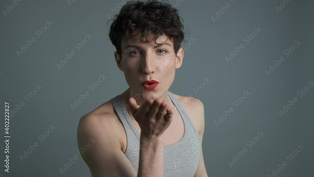 Portrait of handsome transgender man with makeup sending air kiss to