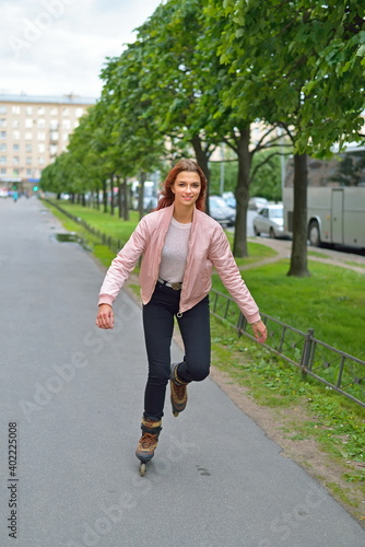 Beautiful girl roller skating through the city in the alley in St. Petersburg