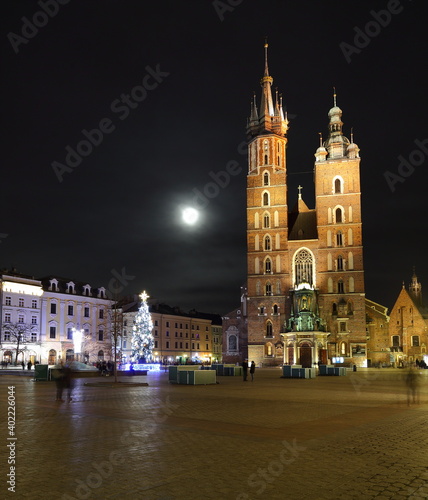 Night cityscape of Krakow old town  saint marys church  Christmas tree decorates main market square  full moon