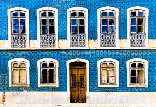 Billede på lærred frontal view of a house facade covered in azulejo tiles with broken windows and