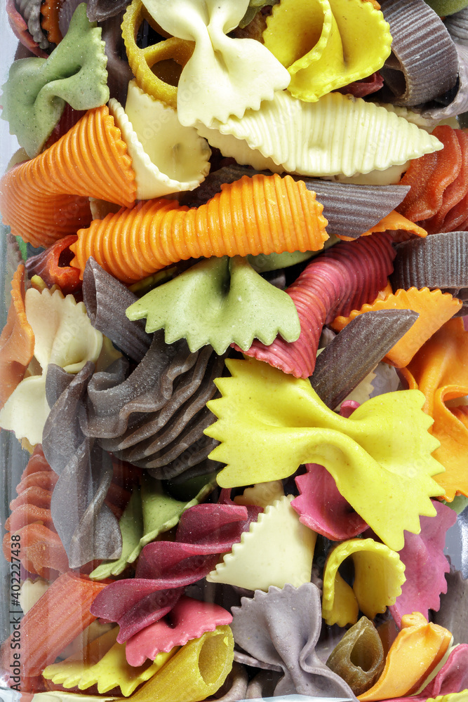 Different colored pasta in a glass, closeup, In the background a wonderful bokeh of orange lights