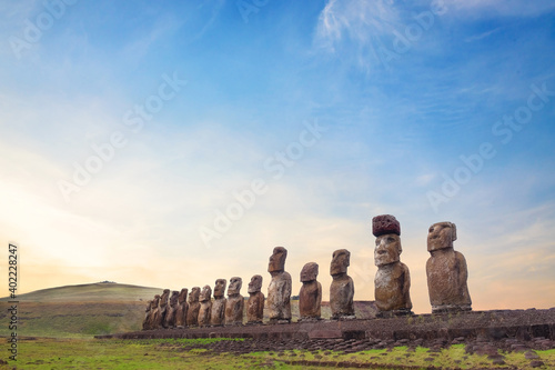 Stone structure and Moai statues at the Ahu Tongariki ceremonial center on Easter Island, against a colorful sky. photo