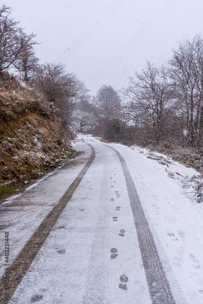Car tracks on the road to mount aizkorri in gipuzkoa. Snowy landscape by winter snows. Basque Country, Spain