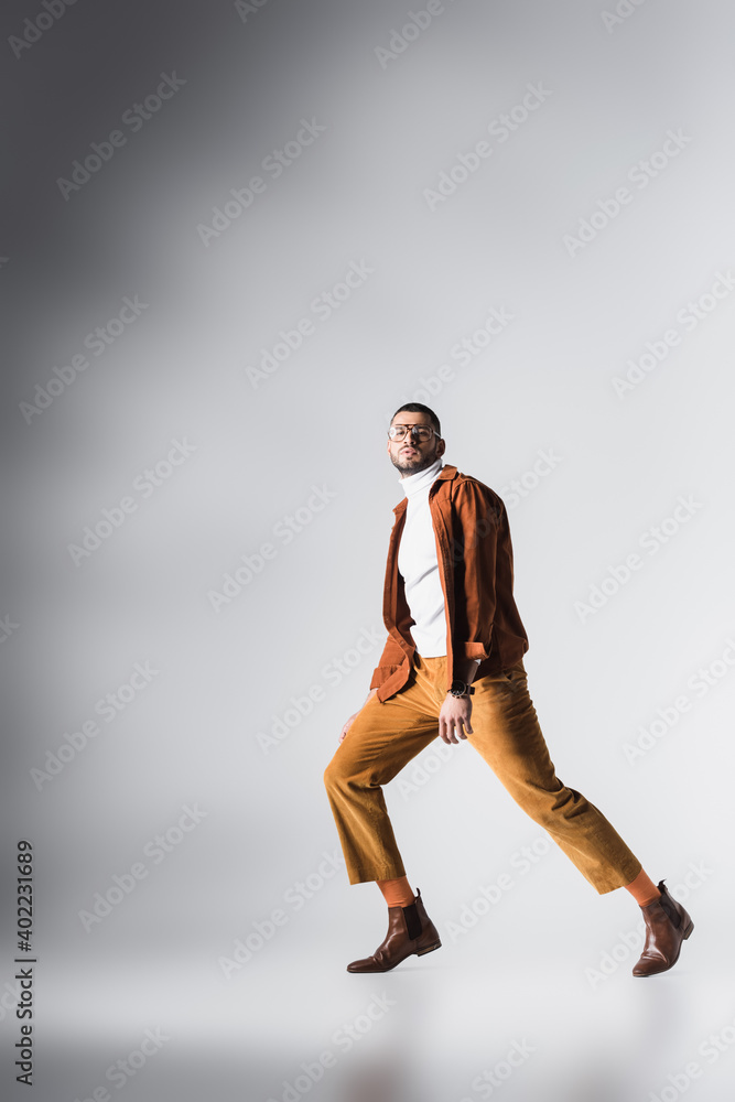 Bearded man in casual clothes looking at camera while posing on grey background Bearded man in casual clothes looking at camera while posing on grey background