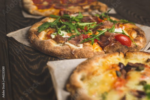 Different pizza in assortment, on wooden background photo