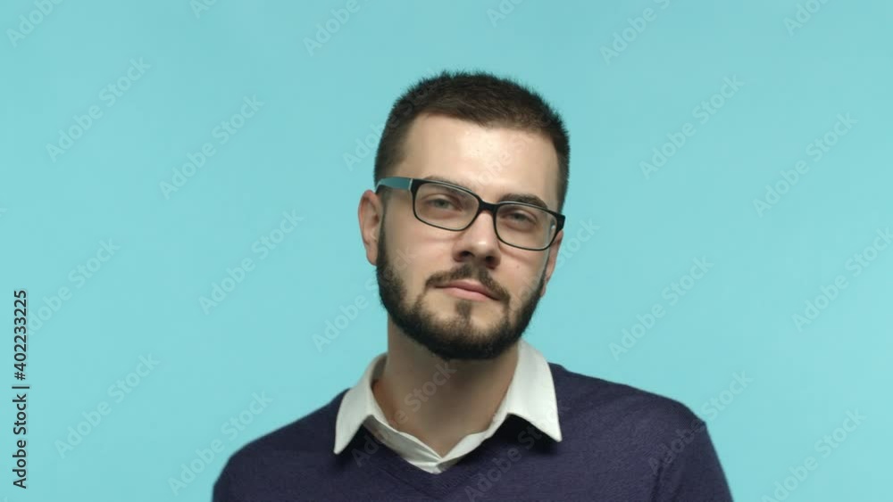 Slow motion of attractive caucasian man with beard and glasses dancing in his office clothes, smiling and partying, standing over blue background Slow motion of attractive caucasian man with beard and glasses dancing in his office clothes, smiling and partying, standing over blue background