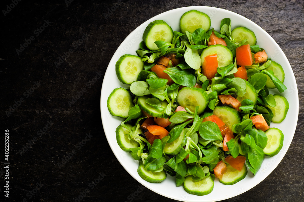 Salad with baby spinach, tomatoes, fresh arugula and cucumber on stoned background . Concept for a tasty and healthy meal.Vitamins in vegetables and herbs for immunity against the virus.Top view. Salad with baby spinach, tomatoes, fresh arugula and cucumber on stoned background . Concept for a tasty and healthy meal.Vitamins in vegetables and herbs for immunity against the virus.Top view.
