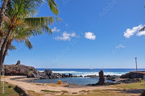 Beach and palm trees near the Hanga Roa village on Easter Island, against a blue sky covered by white clouds. photo