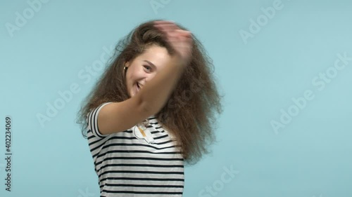 Slow motion of beautiful glamour girl pointing at camera, then beckon everyone come with me, inviting to party, smiling friendly, standing over blue background