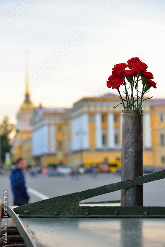 Red carnations in a gun cartridge on a light Soviet tank T-38 in the background of the Admiralty