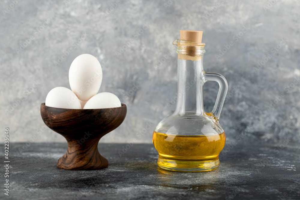 Bowl of white eggs and bottle of oil on marble background Bowl of white eggs and bottle of oil on marble background