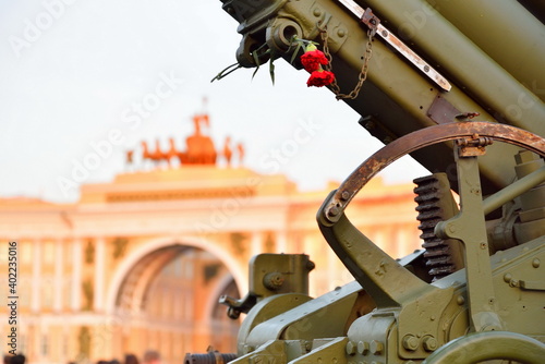 Red carnations on anti-aircraft artillery gun in the background of the Arch of the General Staff on the Day of memory and grief