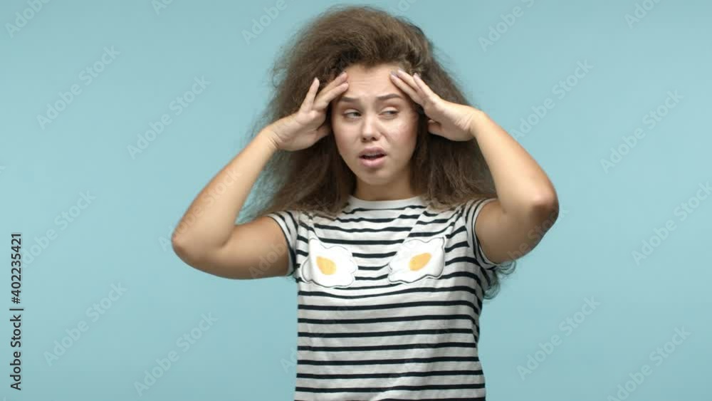 Sad teenage girl looking like drama queen, cover eyes with upset expression, showing no gesture and frowning disappointed, standing distressed against blue background Sad teenage girl looking like drama queen, cover eyes with upset expression, showing no gesture and frowning disappointed, standing distressed against blue background