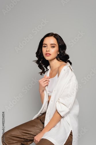  woman in shirt and leather pants looking at camera isolated on grey