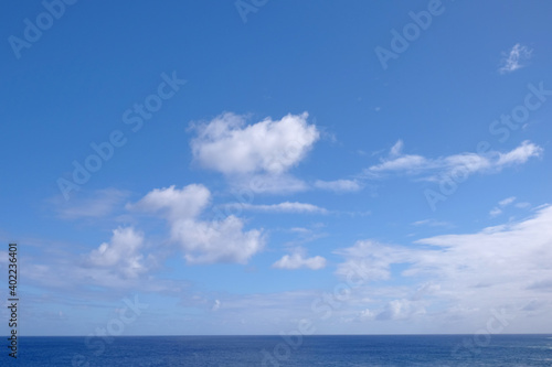 View from the coast of the Easter Island, of blue sky covered by white clouds, over the Pacific Ocean.