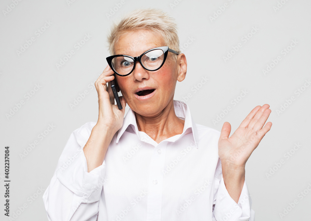 Cheerful senior lady using a mobile and receiving an amazing surprise Cheerful senior lady using a mobile and receiving an amazing surprise