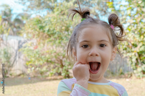 Cute little girl walks on nature and laughs and grimaces looking into the camera. happy childhood and positive emotions. 
