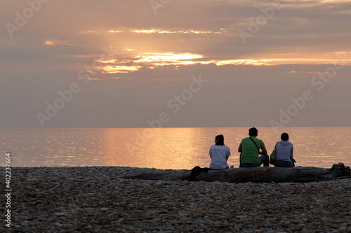 Photos Young people sit by the sea and watch the sunset