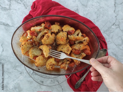 Roasted cauliflowers with tomatoes sauce with a red tablecloth