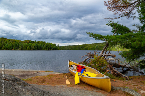 A resting yellow canoe, with life jackets, on the rocky shores of a beautiful small island at Algonquin Park, Ontario, Canada