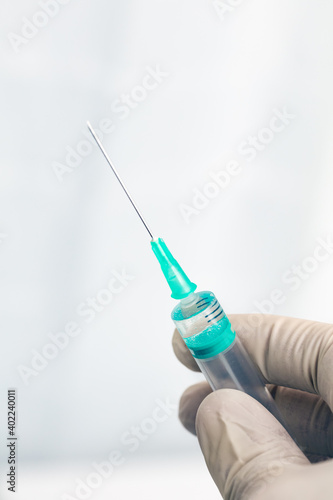 Male hand in white gloves holding a plastic syring with liquid for injection isolated on white background. Health care, vaccination, treatment concept.