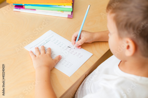 Photography 7 years old child boy doing lessons sitting at desk in his room.
