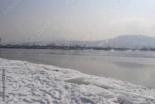 Ice floes in the snow and the Yenisei river against the background of mountains