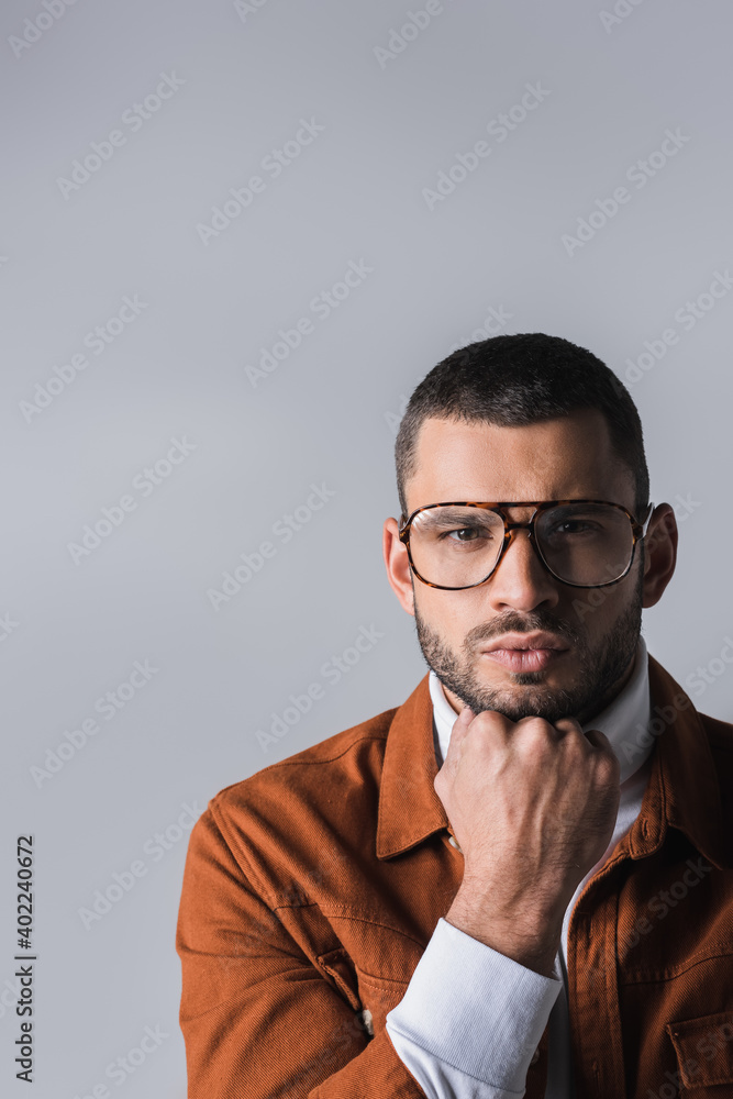 Thoughtful stylish man with hand near chin looking at camera isolated on grey Thoughtful stylish man with hand near chin looking at camera isolated on grey