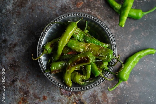 Blistered shishito peppers in a bowl on dark moody setting photo