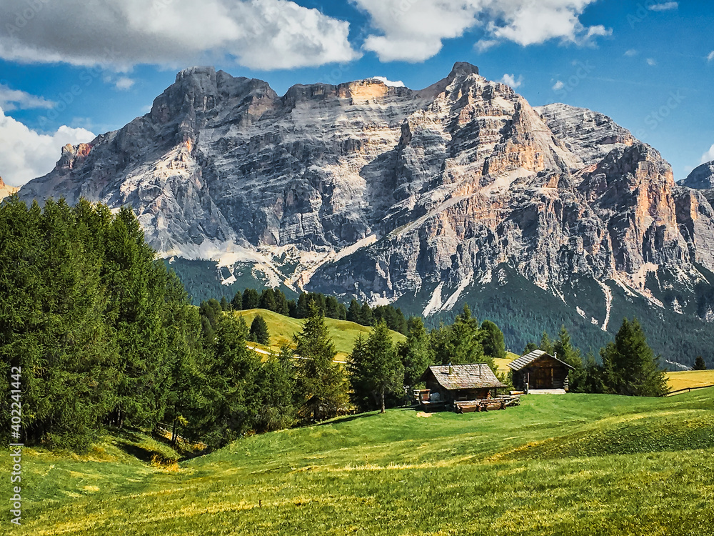Hiking trails through alpine meadows with an isolated cabin in the distance in  the  Dolomites in Italy.
