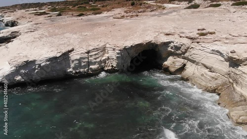 Drone footage of Sea Views from the island of love, Cyprus  with waves hitting on the pure white rocks in the village of alaminos.
people enjoy the sounds of the water touring the caves and suntanning photo