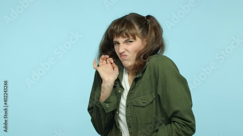 Slow motion of young woman cringe from something disgusting, feeling awkward and displeased, grimacing with aversion, staring at something awful, standing over turquoise background