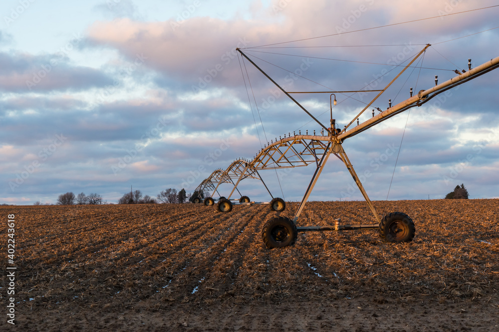 Fototapeta premium Rural sunset on a field with irrigation equipment