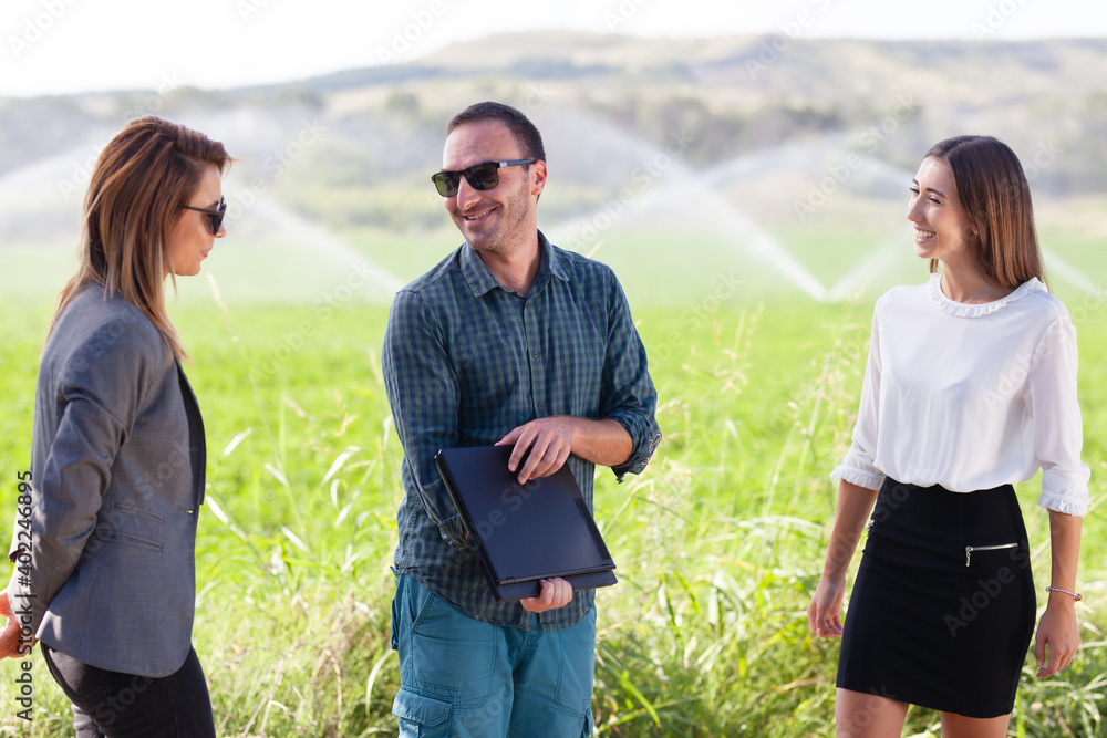 Business people in a green field with agriculture irrigation system.