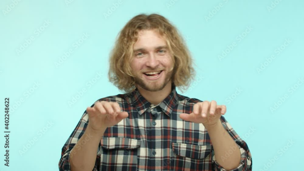 Slow motion of handsome blond man with beard and long wavy hair, playing on air piano and smiling joyfully, standing happy against blue background Slow motion of handsome blond man with beard and long wavy hair, playing on air piano and smiling joyfully, standing happy against blue background