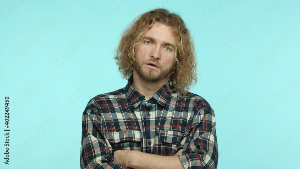 Slow motion of tired skeptical man with blond wavy hair and beard, exhale annoyed and cross arms on chest, looking with disbelief and judgement, scolding someone, turquoise background Slow motion of tired skeptical man with blond wavy hair and beard, exhale annoyed and cross arms on chest, looking with disbelief and judgement, scolding someone, turquoise background