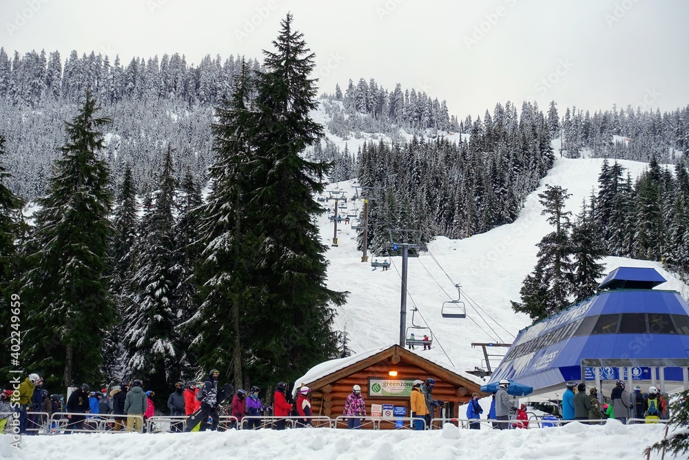 A group of skiers and snowboarders waiting in line to hitch a ride up the ski lift on Cypress Mountain on a beautiful snowy winter day