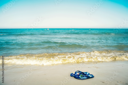Flip flops on the beach near the blue sea