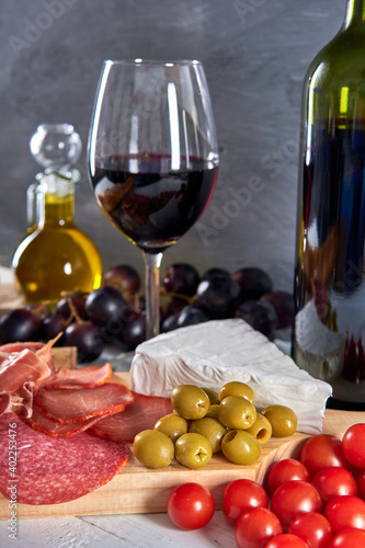 Fototapeta Naklejka Na Ścianę i Meble -  meat platter and wine. a variety of hams, olives, tomatoes,grapes and brie cheese.(Antipasto or tapas)