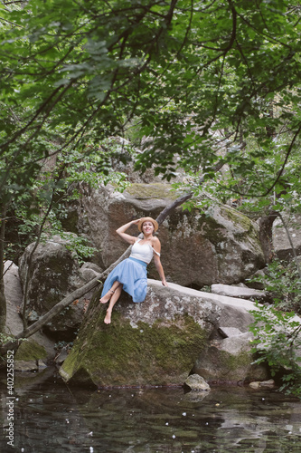 A girl in a blue skirt is walking in a beautiful forest