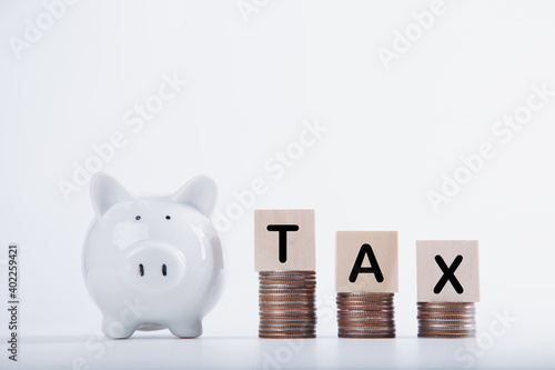 Wooden cubes with the word Tax on money climbing staits and pig piggy bank. Tax Concept background closeup. photo