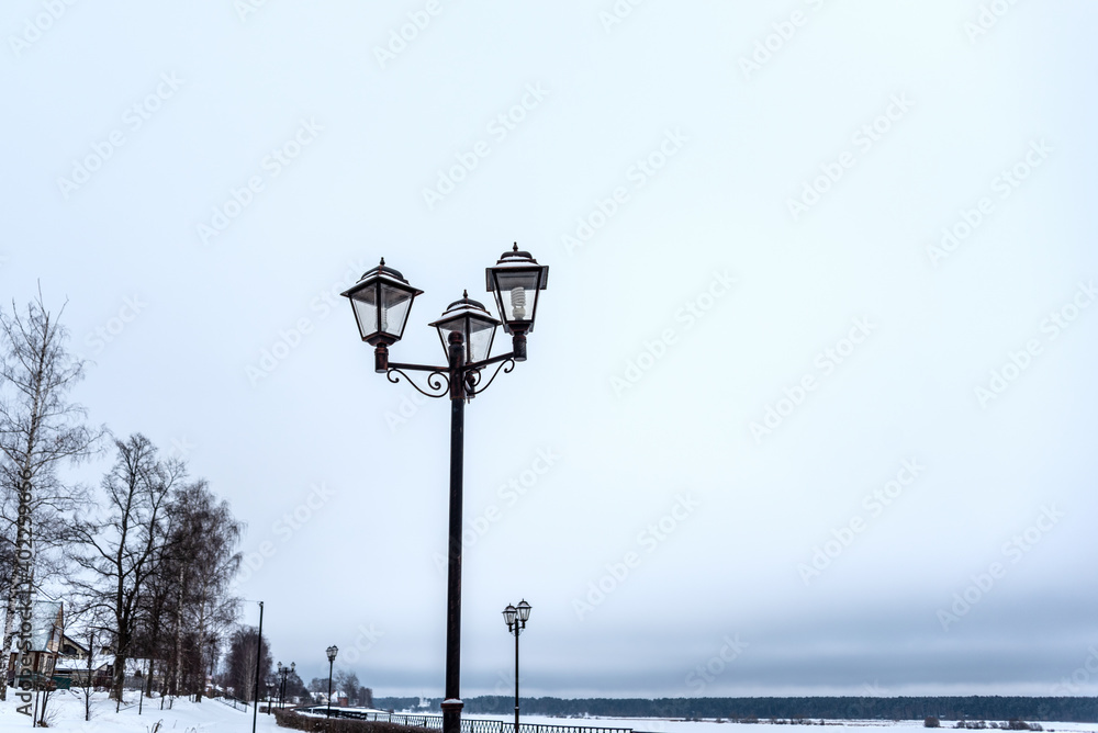 Street lights on the embankment of the frozen river. Minimalistic sketching.