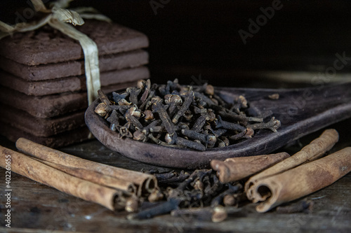 cloves in a wooden spoon and cinnamon