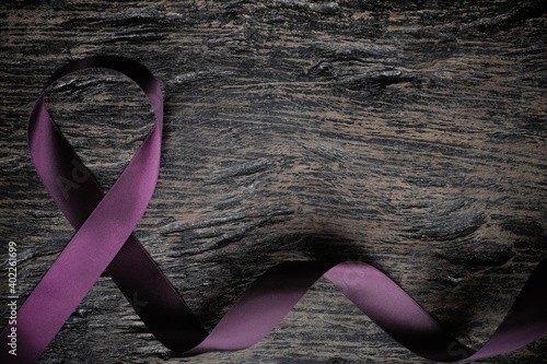 Top view of purple ribbon on wood background with copy space. Pancreatic cancer, epilepsy, leiomyosarcoma, lupus, Alzheimer's disease and cystic fibrosis awareness concept. photo